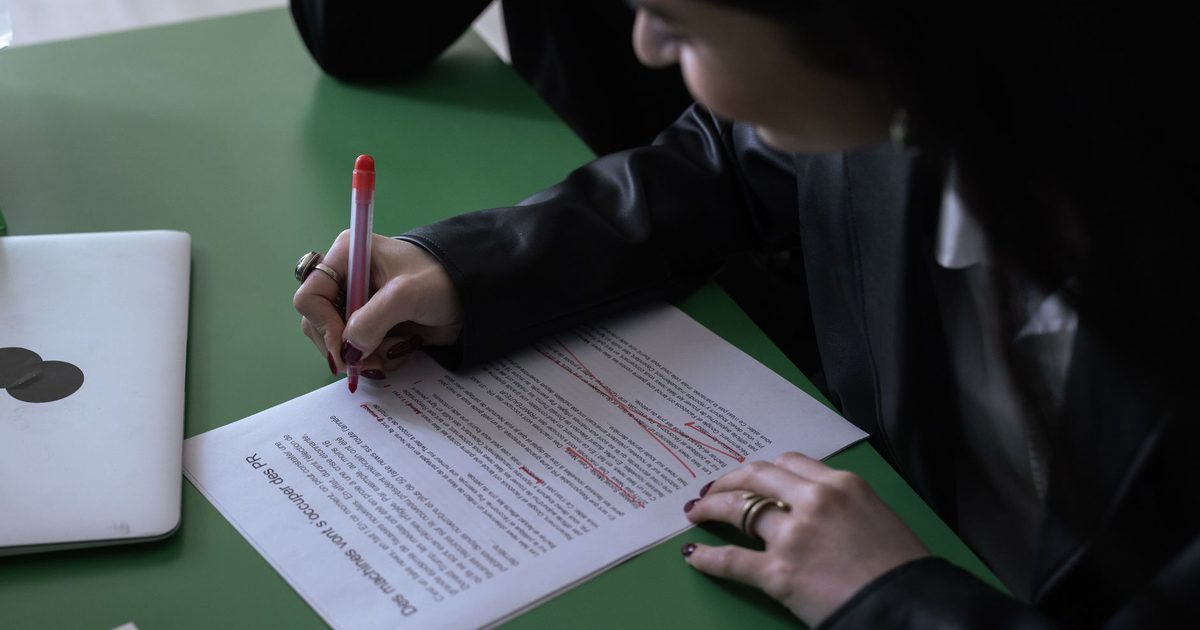 印刷した文書に赤ペンで手を入れている人